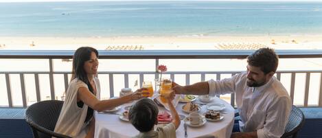 A family dining at a table with a view of the beach.