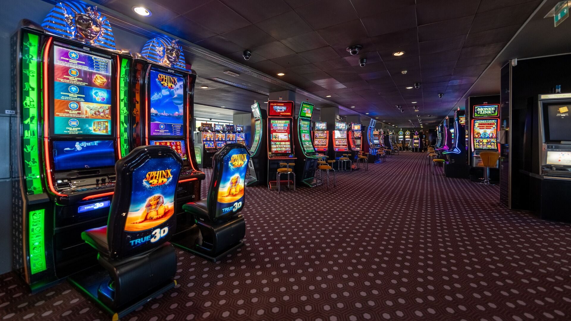 Ein Casino-Bereich mit mehreren Spielautomaten und einem gemusterten Teppich.