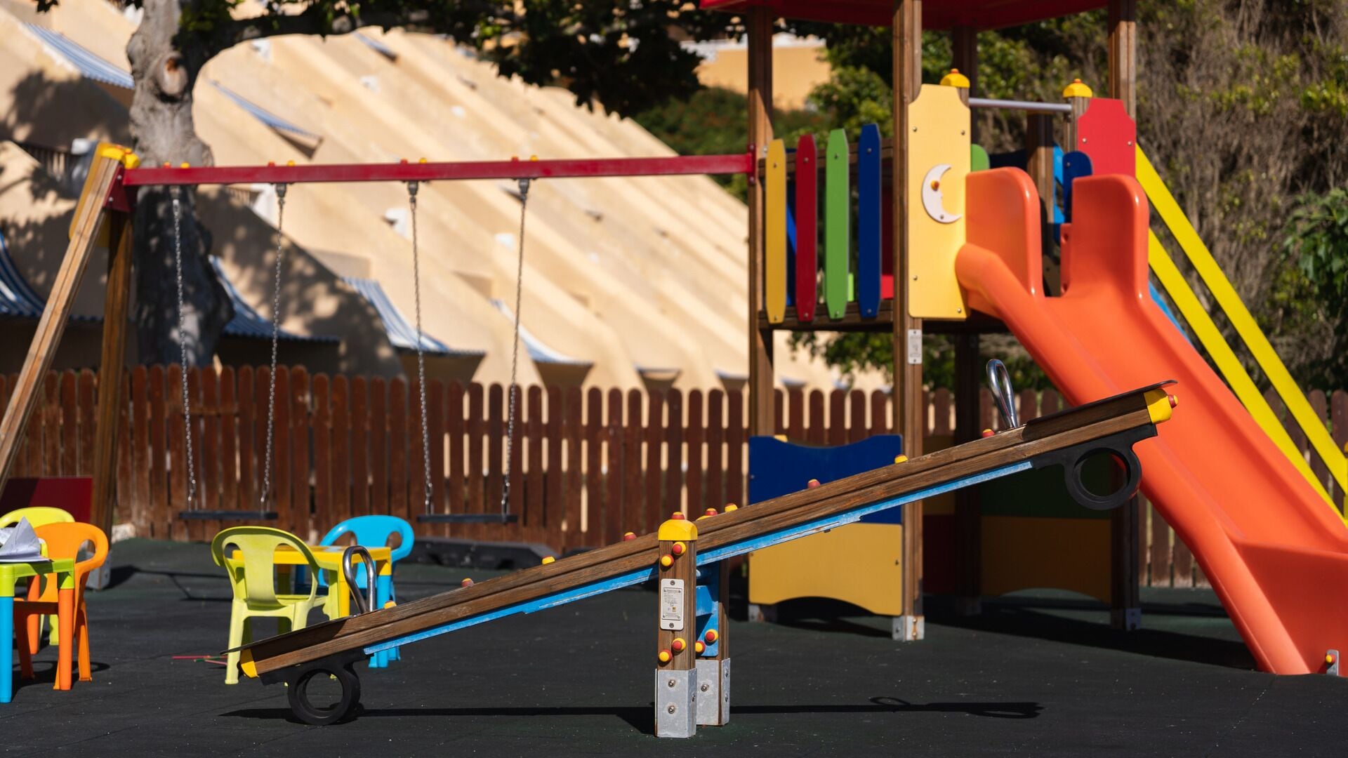 A playground with a seesaw, slide, and swings.