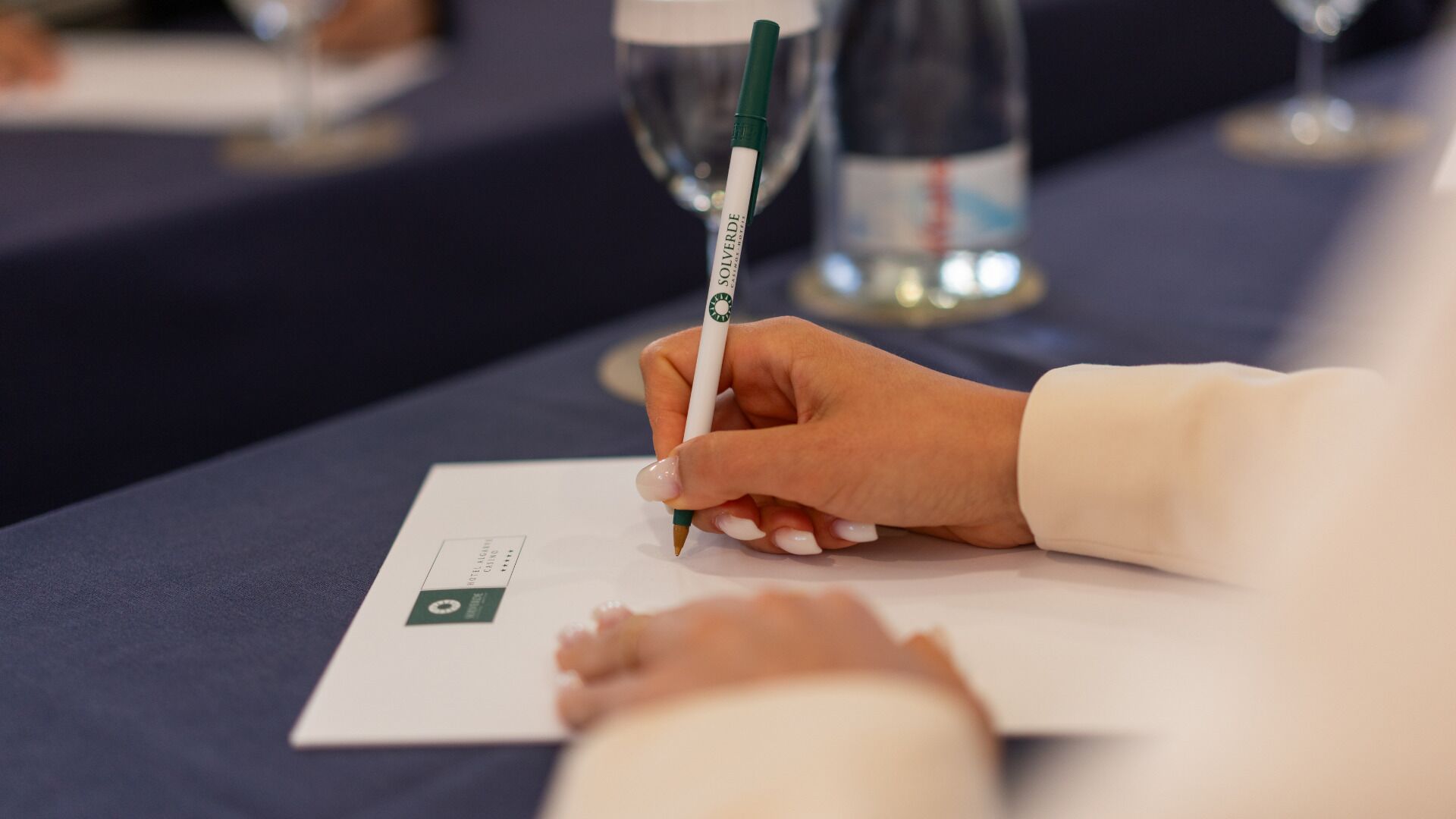 A person writing on a piece of paper with a pen.