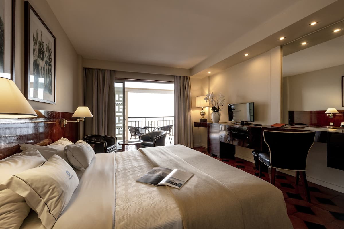 Een hotelkamer met een groot bed, een bureau, een stoel, een televisie en een balkon met uitzicht.