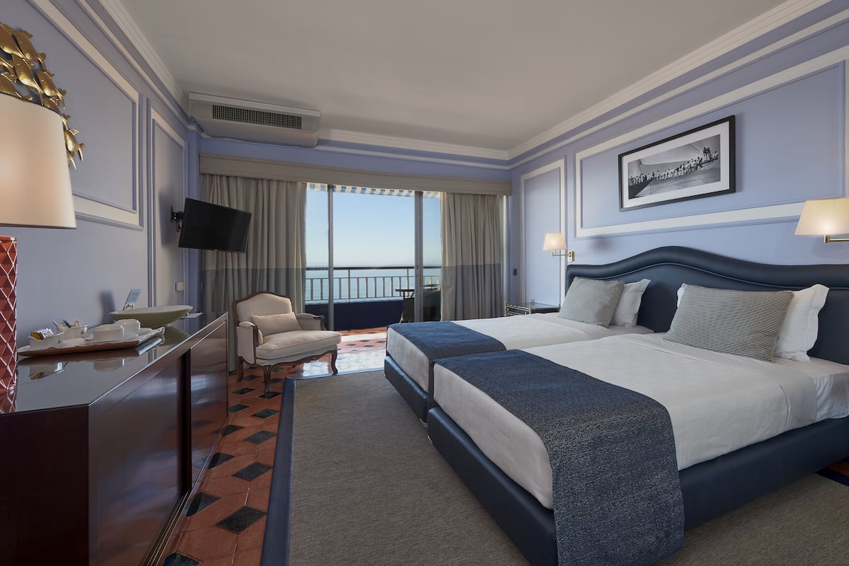 Hotelkamer met een groot bed, een bureau met stoel, een televisie en een balkon met uitzicht.