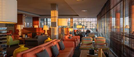 A modern hotel lobby with a seating area, large windows, and contemporary decor.