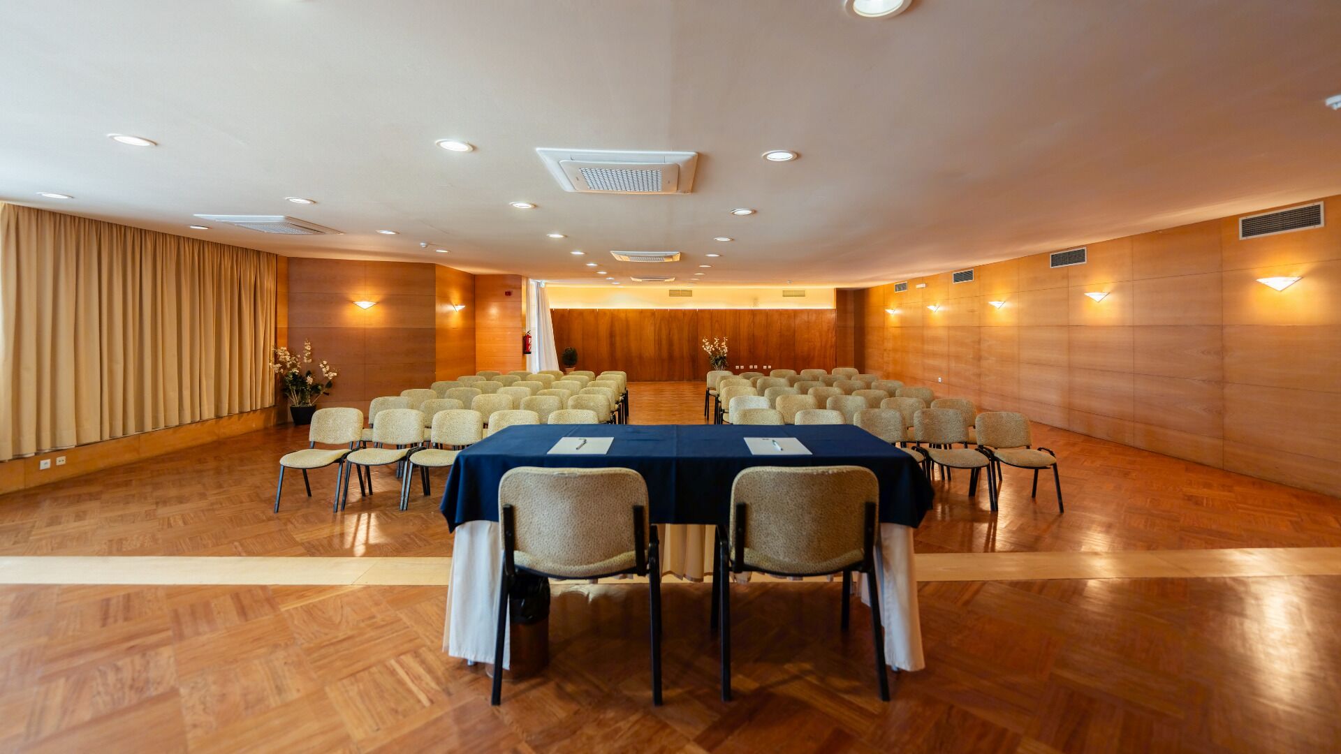 A conference room with a long table, chairs, and a stage.