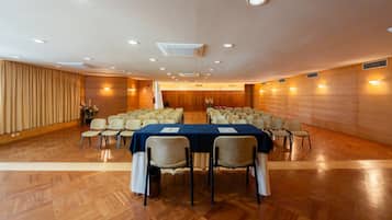 A conference room with a long table, chairs, and a stage.