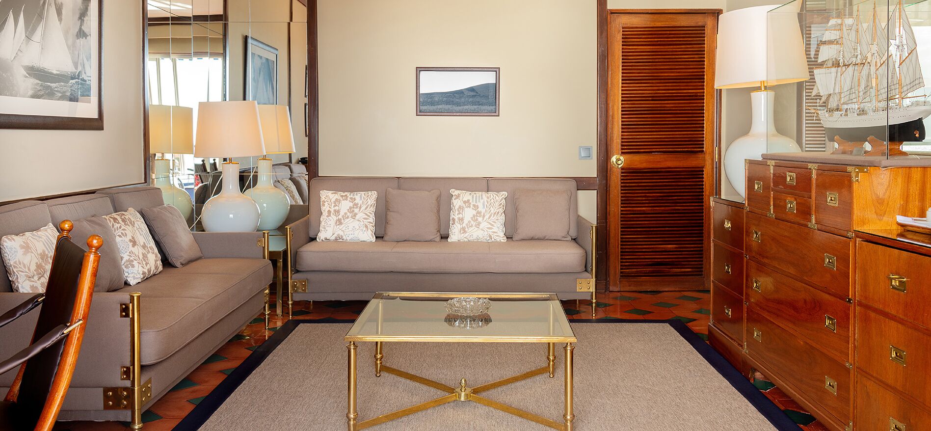 Un salon comprenant un canapé, une table basse en verre, un meuble en bois et une lampe.