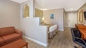 Una habitación de hotel con sofá, escritorio, cama y una pequeña mesa.