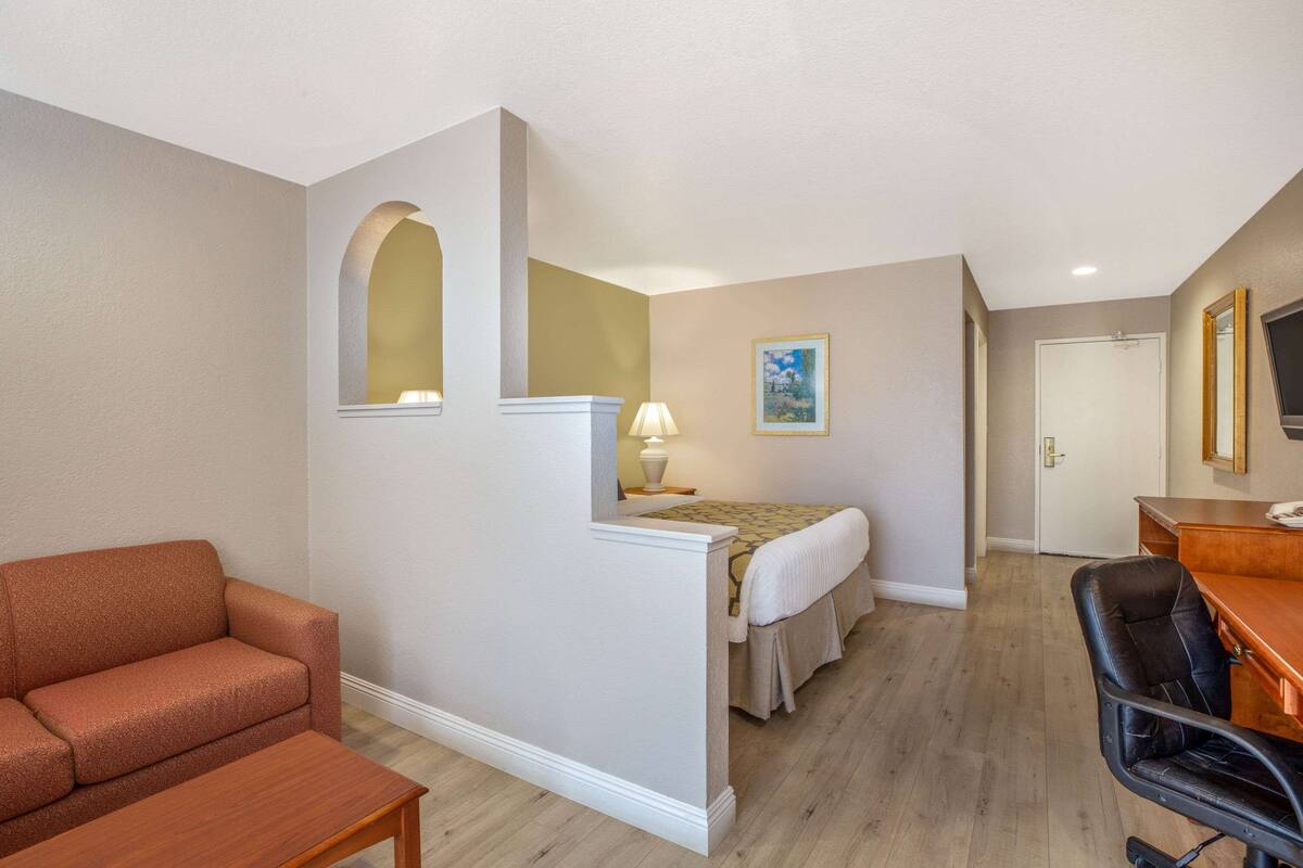 Una habitación de hotel con sofá, escritorio, cama y una pequeña mesa.