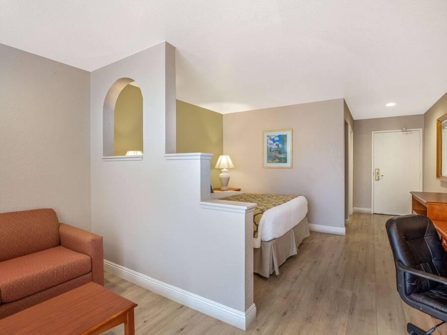 Una habitación de hotel con sofá, escritorio, cama y una pequeña mesa.