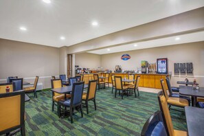 Enjoy a meal at our dining area with tables, chairs, and a central bar offering a selection of beverages and snacks.
