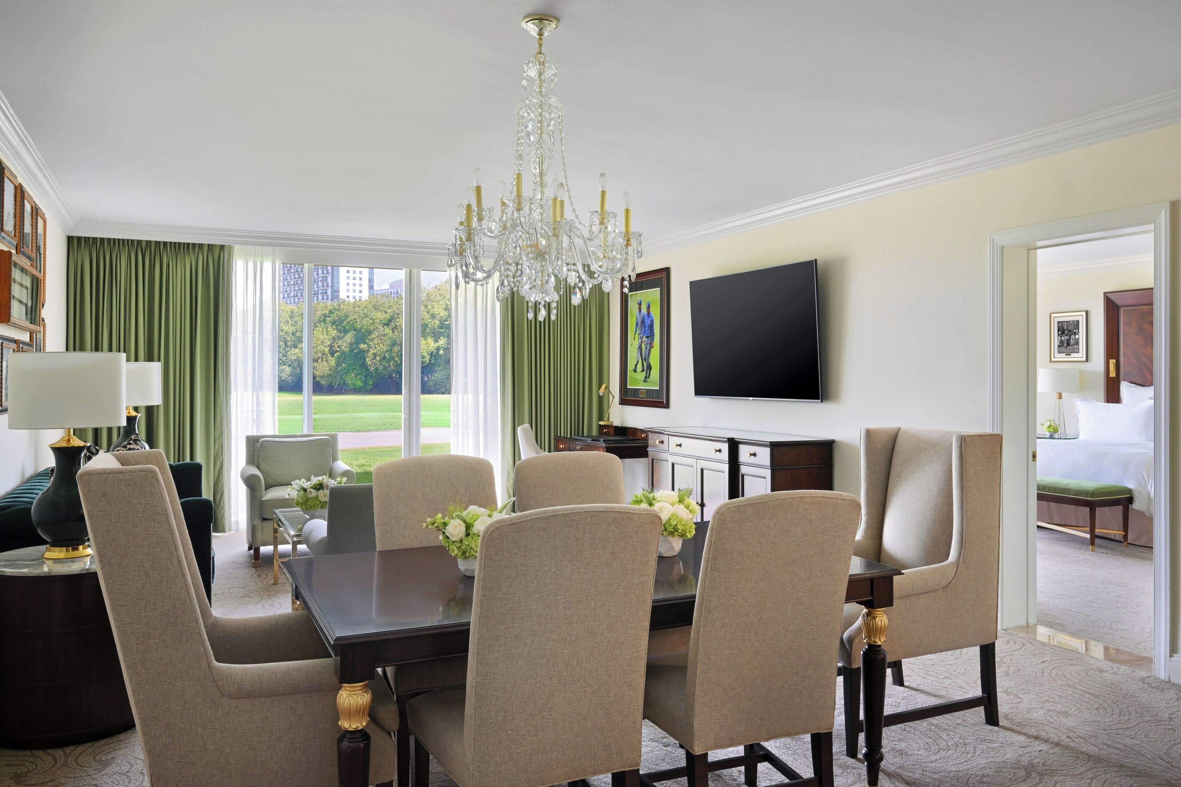 Un comedor con candelabro, televisor y vistas al exterior.