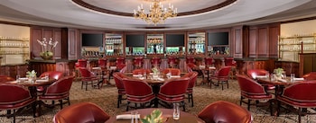 A large, well-lit room with patterned carpet, large windows with yellow curtains, and chandeliers. at Trump National Doral Miami