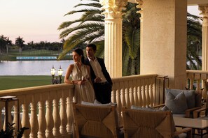 A couple on a balcony with a view of a lake and palm trees. - Trump National Doral Miami (Miami)