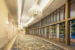 A long corridor with a patterned carpet, large windows, and a chandelier. - Trump National Doral Miami (Miami)