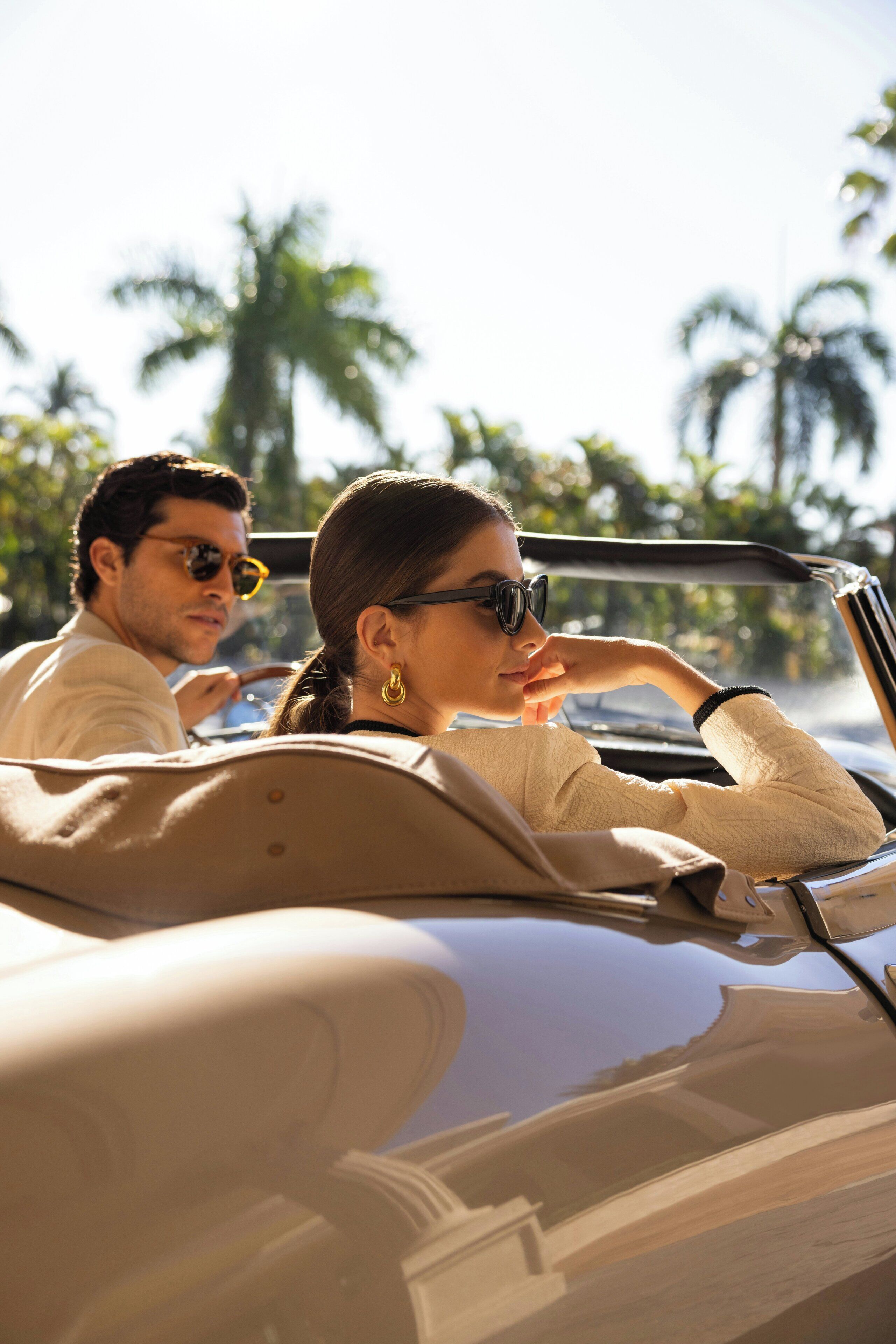 A convertible car with a man and a woman seated inside.