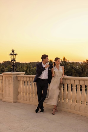 A couple on a balcony with a sunset view, a lamp post, and a railing. - Trump National Doral Miami (Miami)