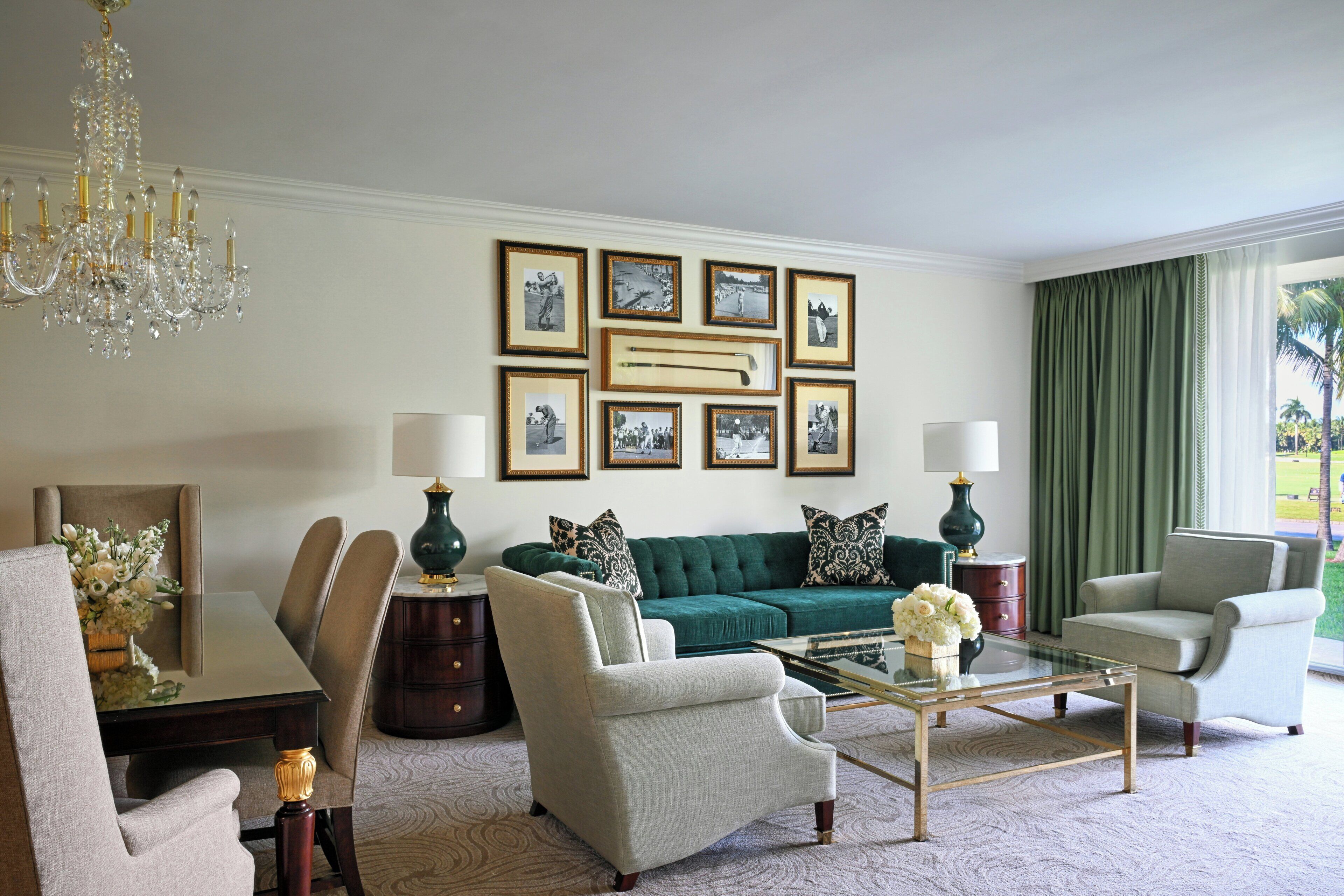 A well-appointed living room with a green sofa, two armchairs, a glass coffee table, and a chandelier.