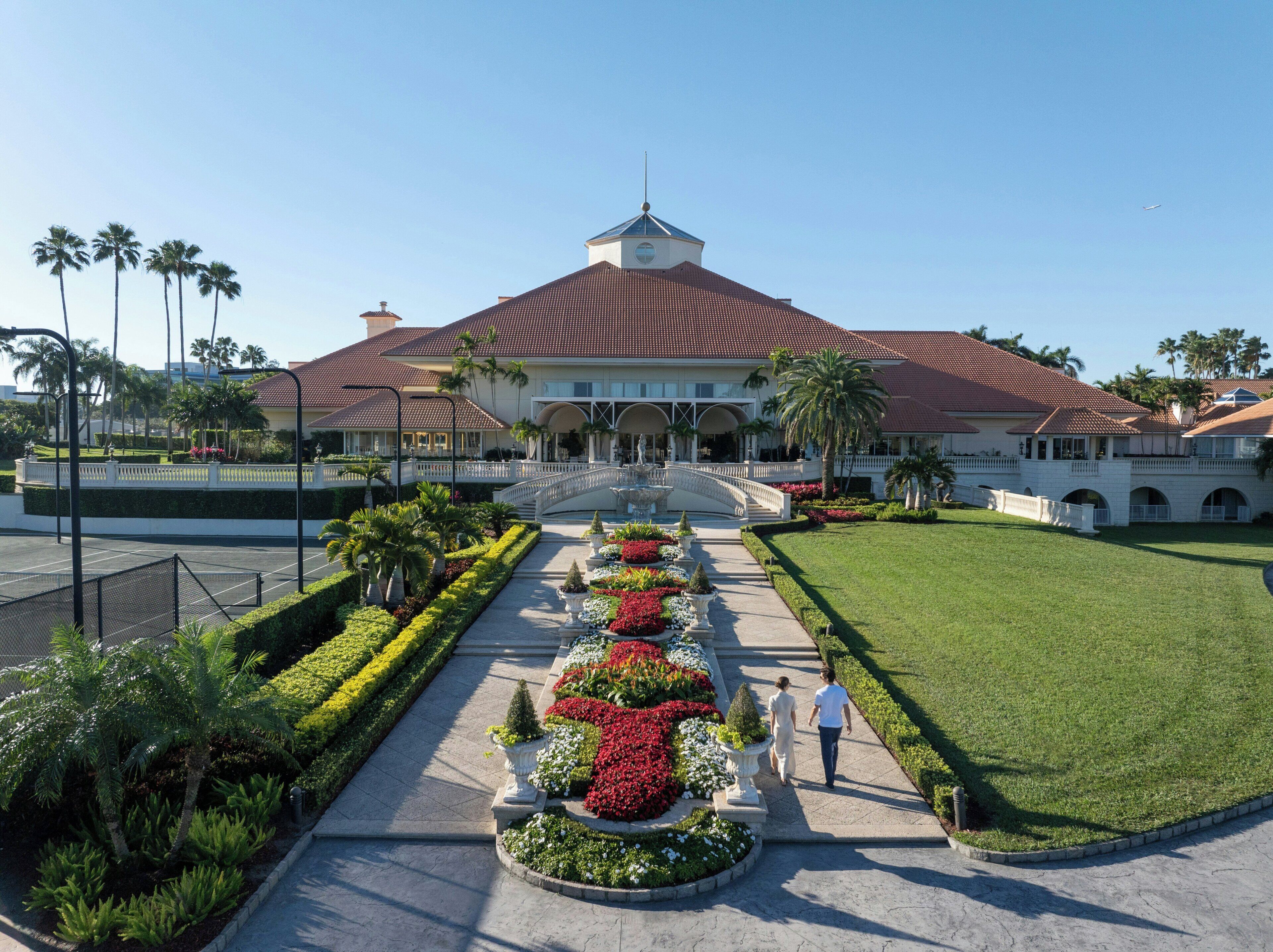 A large building with a central courtyard, a bridge, and a tennis court.