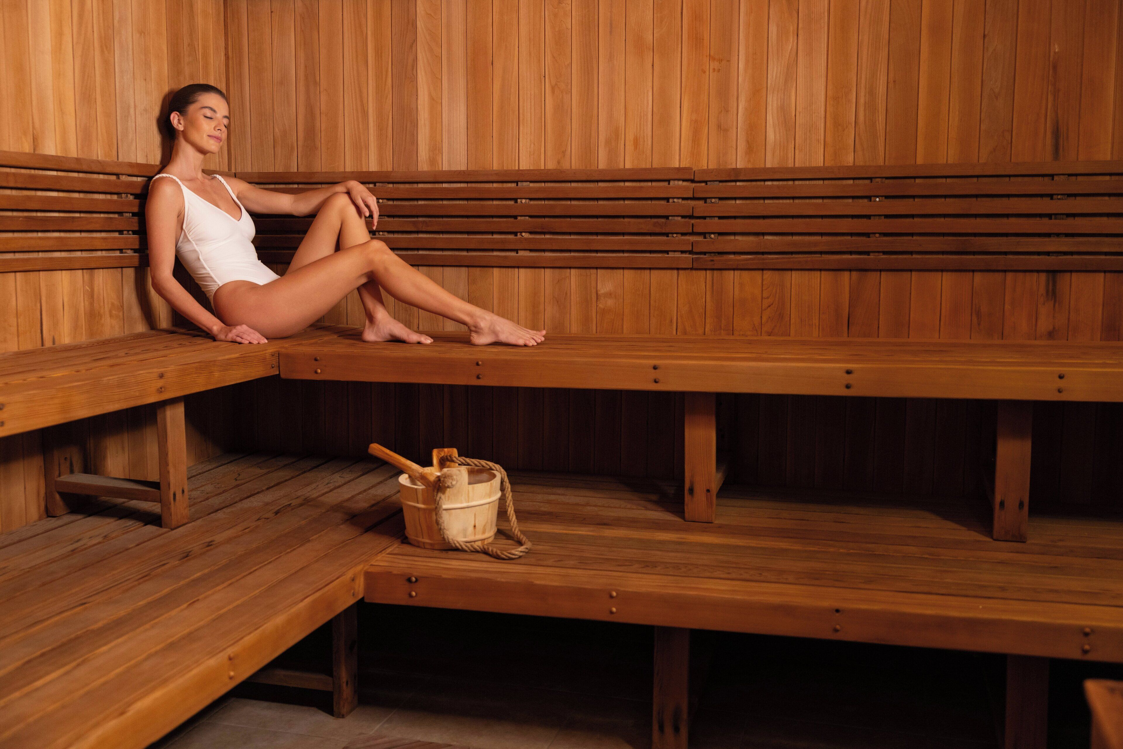 A sauna with wooden benches and a bucket with a brush.