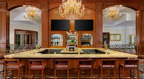 A bar area with a marble counter, multiple chairs, and a large chandelier. - Trump National Doral Miami (Miami)