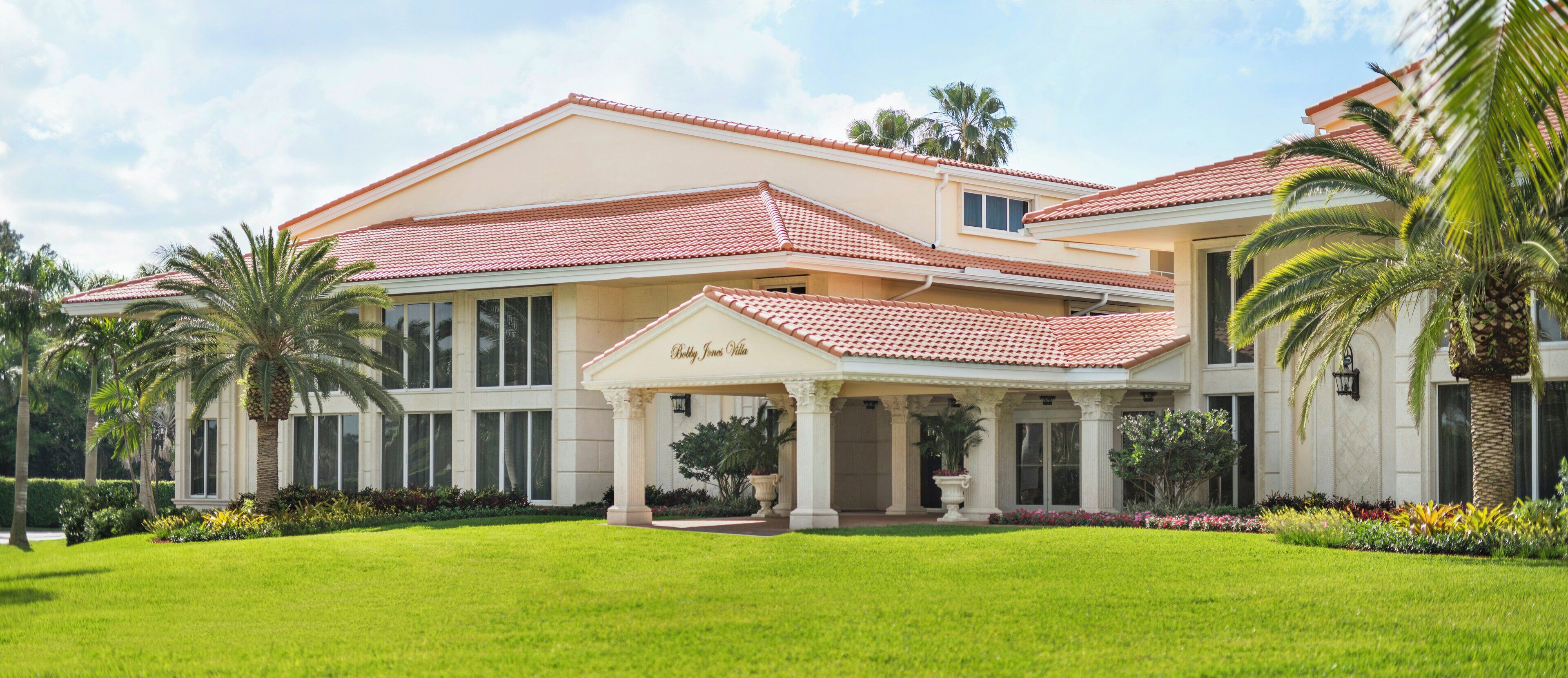 A large, two-story building with a red-tiled roof and a covered entrance area.
