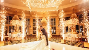 A grand ballroom with a white floor and ornate chandeliers, surrounded by tables set for a wedding reception. - Trump National Doral Miami (Miami)