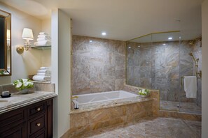 Un baño moderno con lavamanos de mármol, bañera y zona de ducha con paredes de vidrio.
