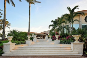 A grand entrance with a staircase leading to a covered area, surrounded by lush greenery and palm trees. - Trump National Doral Miami (Miami)