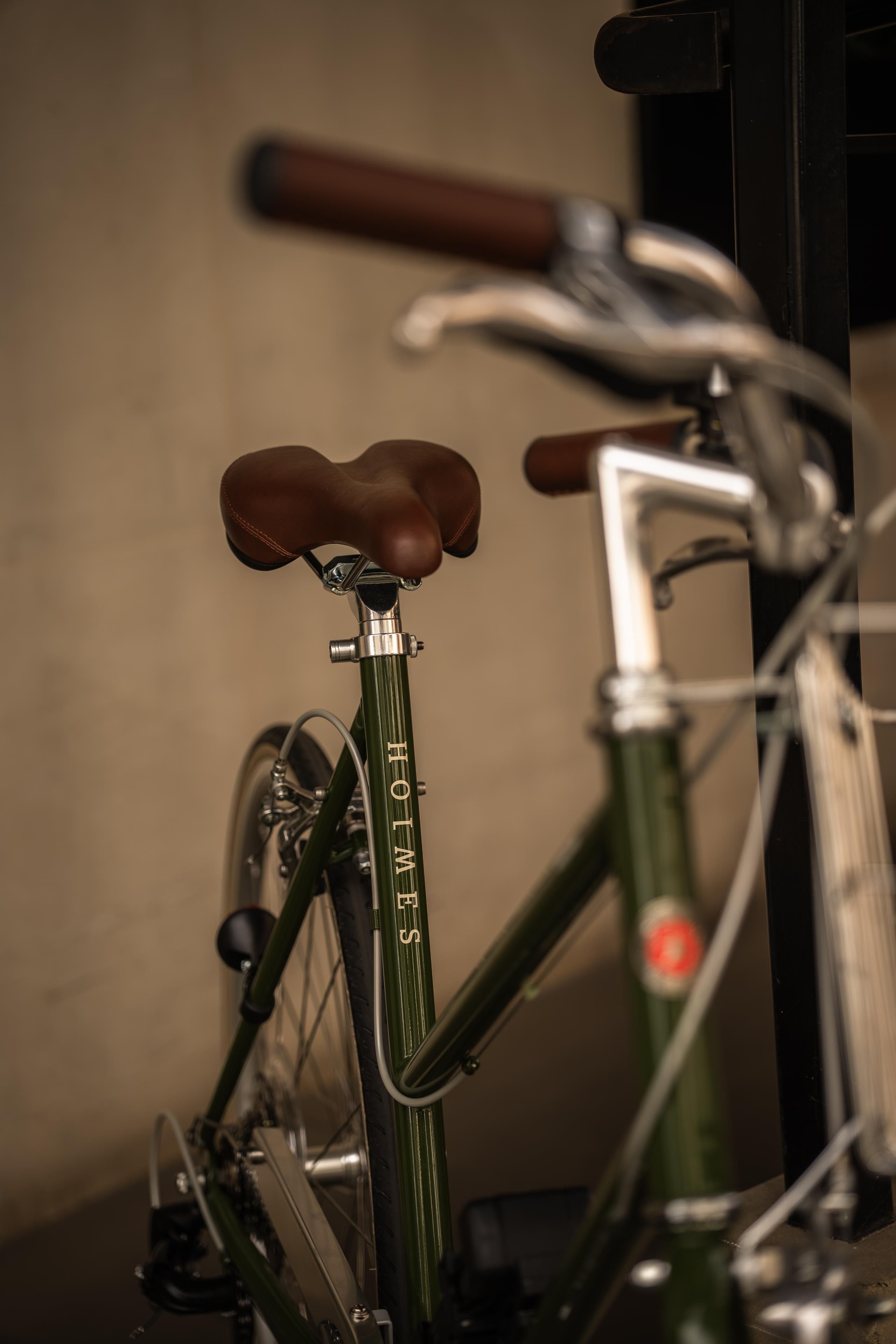 Ein Fahrrad mit Ledersattel und Flaschenhalter, das an einer Wand angelehnt ist.