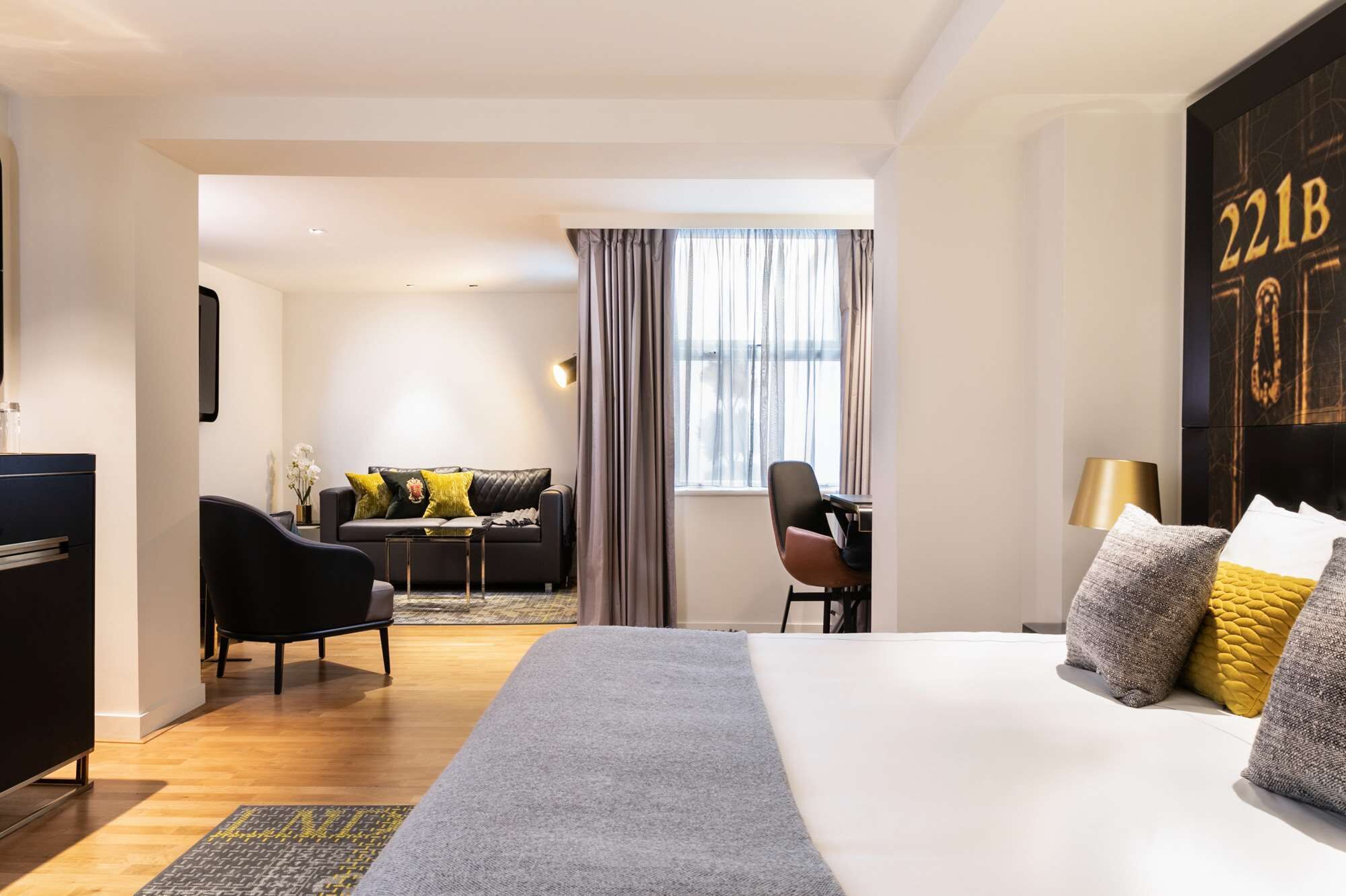 A hotel room with a large bed, a desk, a sofa, and a view of the outside through a window.