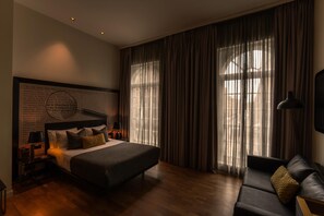 A modern hotel room with a large bed, a sofa, and a view through sheer curtains. - Holmes Hotel London (London)