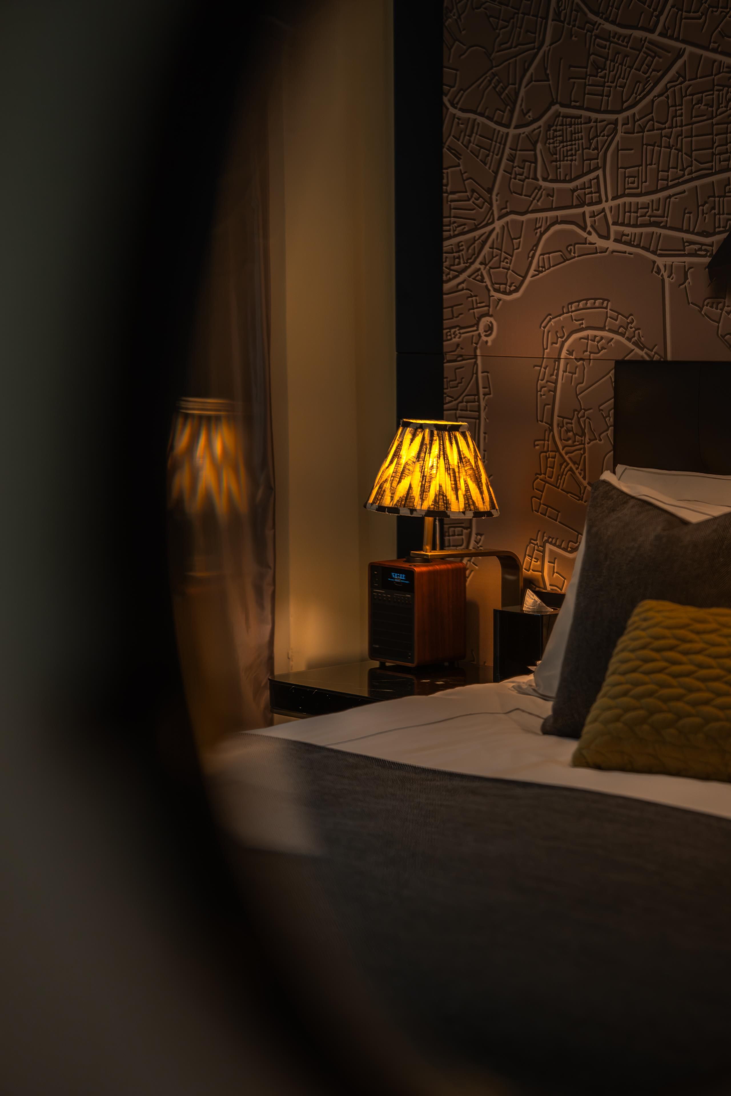 Une chambre d’hôtel avec un lit, une table de chevet, une lampe et une carte géographique accrochée au mur.