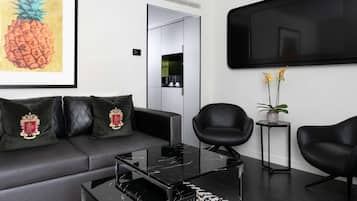 A modern living room with a sofa, two armchairs, a coffee table, and a flat-screen TV mounted on the wall.
