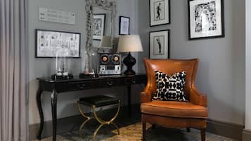 A room with a desk, a chair, a mirror, framed pictures, and a sign indicating room numbers.