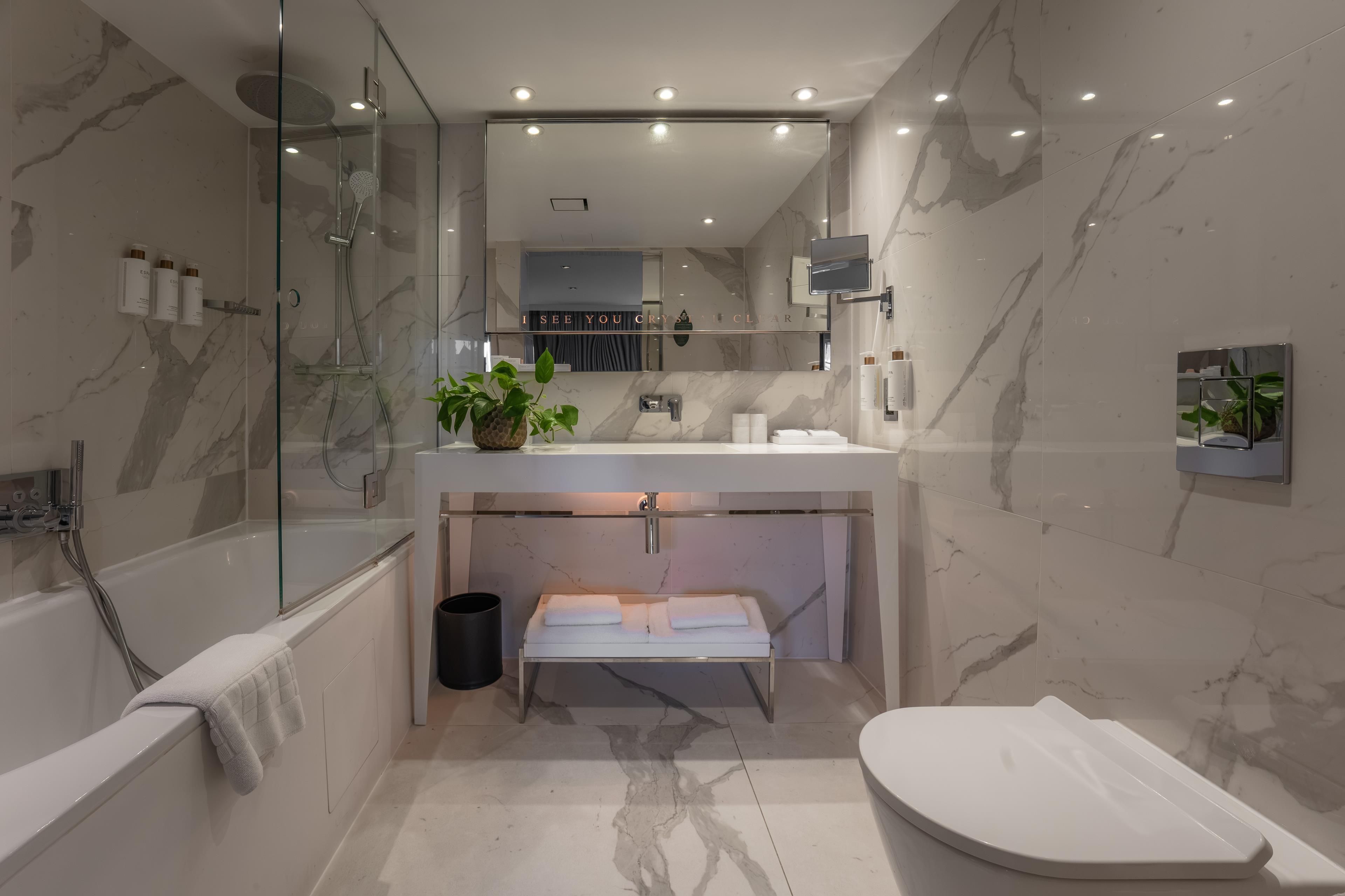 A modern bathroom with a glass-enclosed shower, a vanity with a mirror, and a toilet.