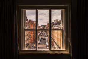 A window with a view of a city street, buildings, and parked cars. - Holmes Hotel London (London)