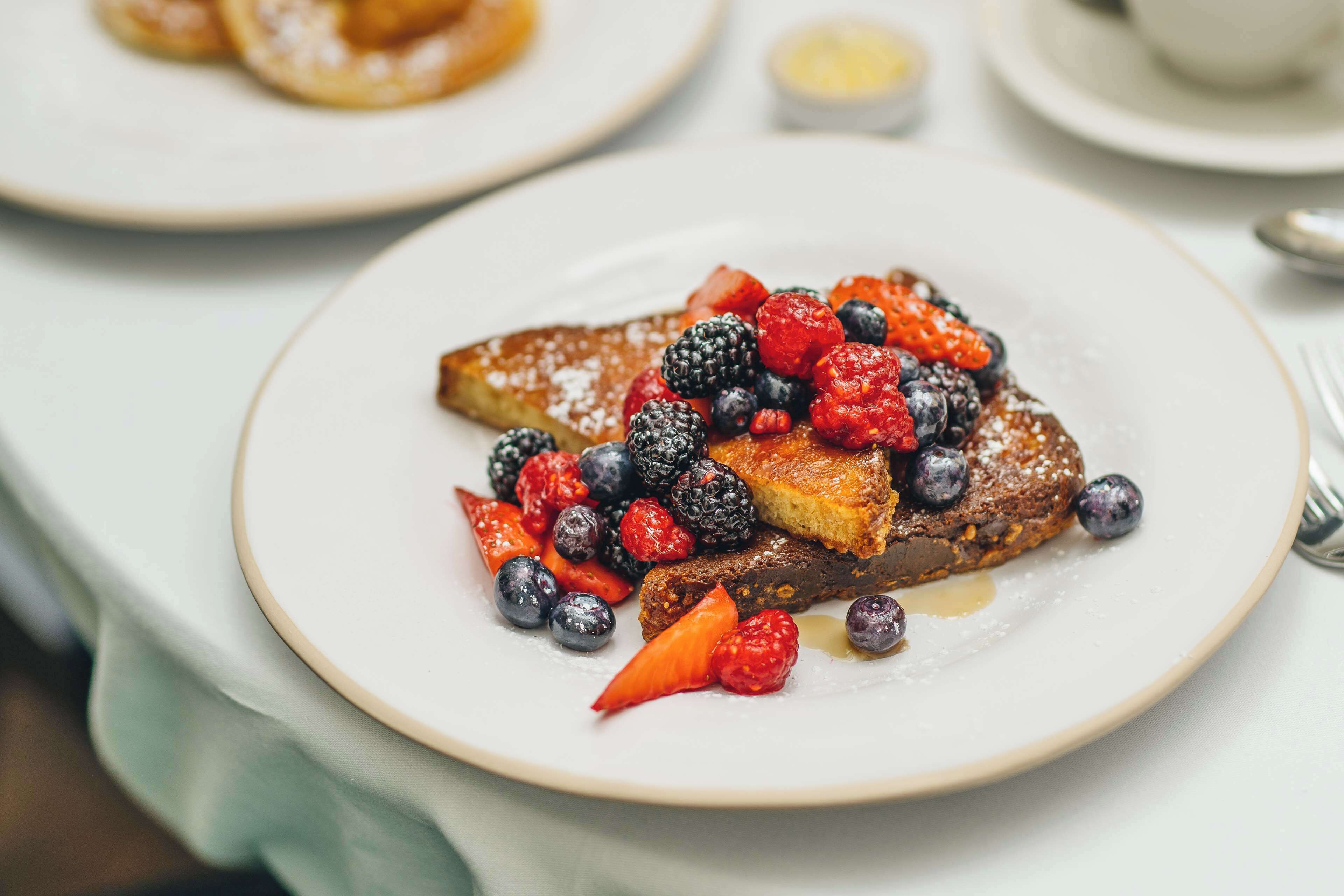 A breakfast plate with French toast, berries, and syrup.