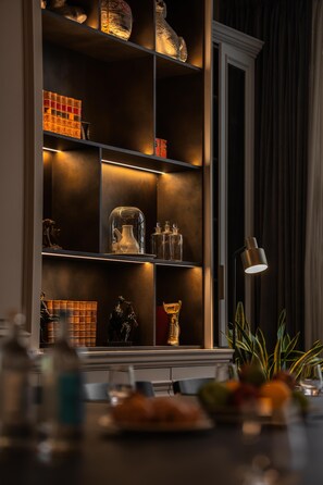 A well-lit interior space with a bookshelf, decorative items, and a table with fruits. - Holmes Hotel London (London)