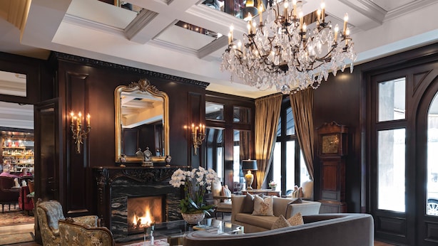 A luxurious living room with a fireplace, elegant furniture, and a large chandelier. - Wedgewood Hotel & Spa (Vancouver)