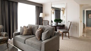 A modern living room with a grey sofa, matching armchairs, a dining table, and a large mirror. - Wedgewood Hotel & Spa (Vancouver)