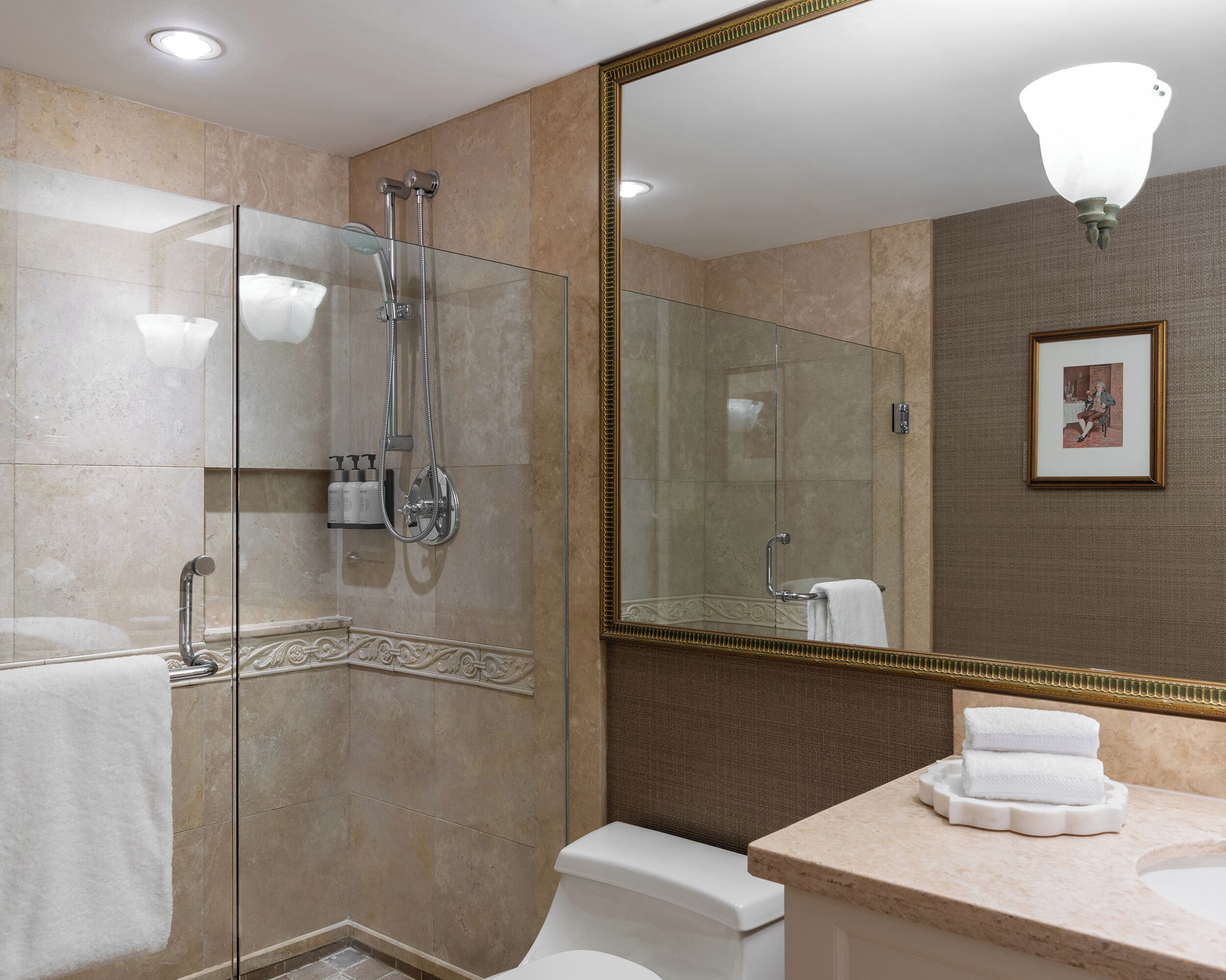 A modern bathroom with a glass-enclosed shower, a large mirror, and a vanity with a sink and towel rack.
