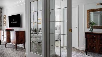 A room with a large mirror, a television, and a wooden cabinet.