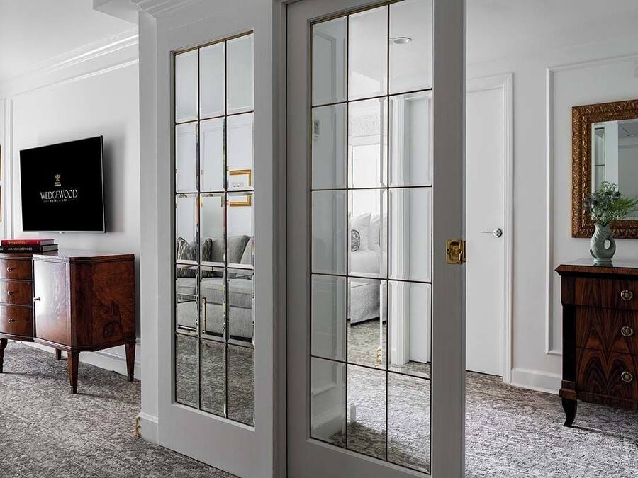 A room with a large mirror, a television, and a wooden cabinet.