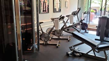 Un gimnasio con equipo de ejercicio, una banca y una pared con cuadros enmarcados.