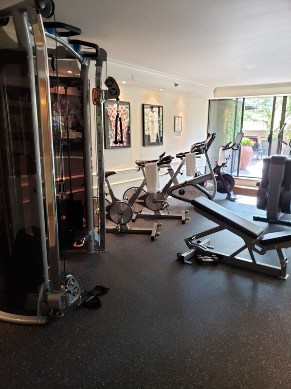 A gym with exercise equipment, a bench, and a wall with framed pictures.