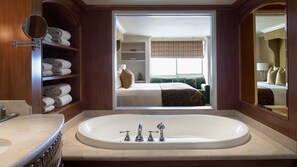 A bathroom with a large bathtub, a mirror, and shelves with towels. - Wedgewood Hotel & Spa (Vancouver)