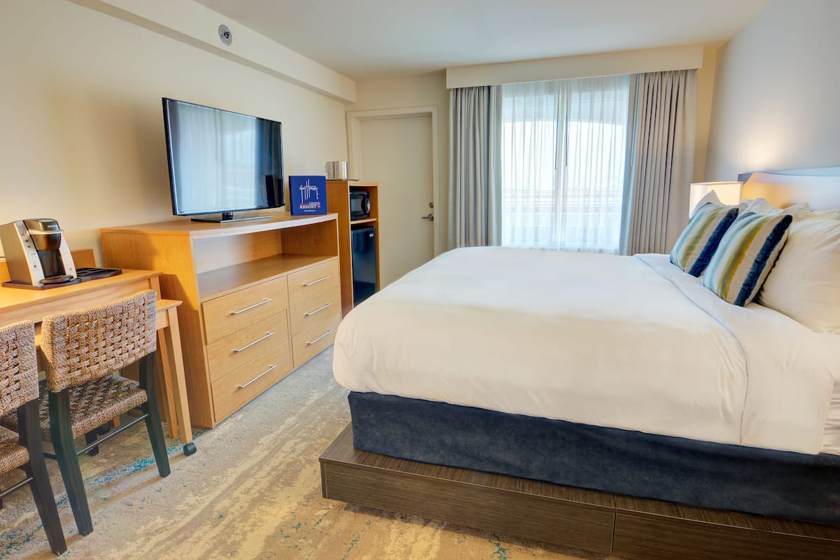 Hotelkamer met een groot bed, een bureau met televisie, een koffiezetapparaat en een minibar.