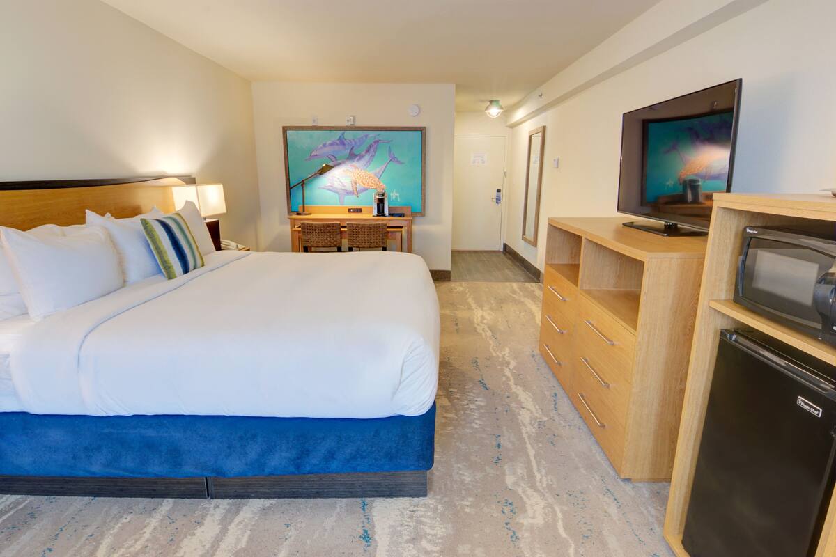 Hotelkamer met een groot bed, een bureau met een computer, een flatscreen televisie en een koelkast.