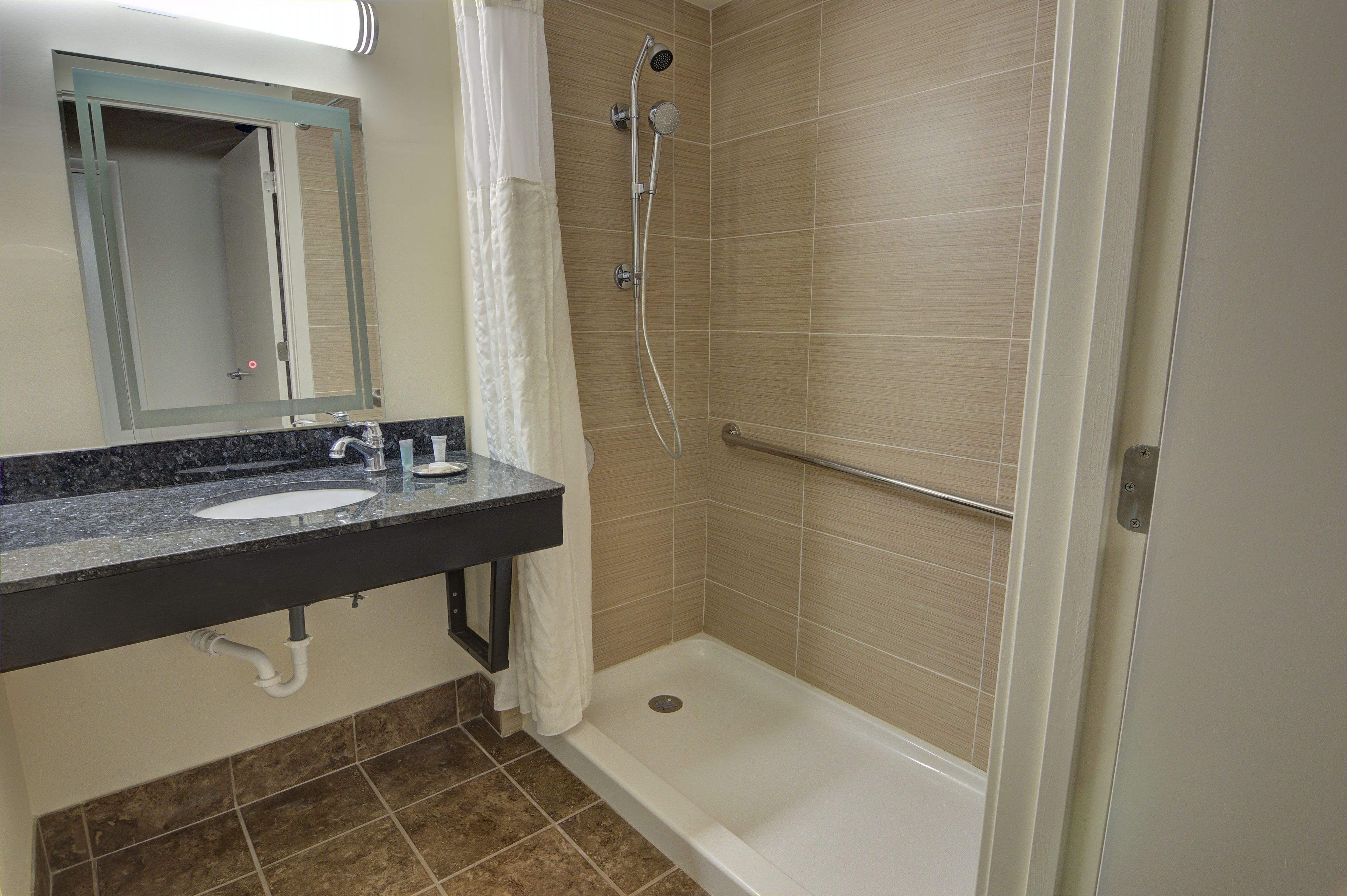 A bathroom with a sink, mirror, shower, and toilet.