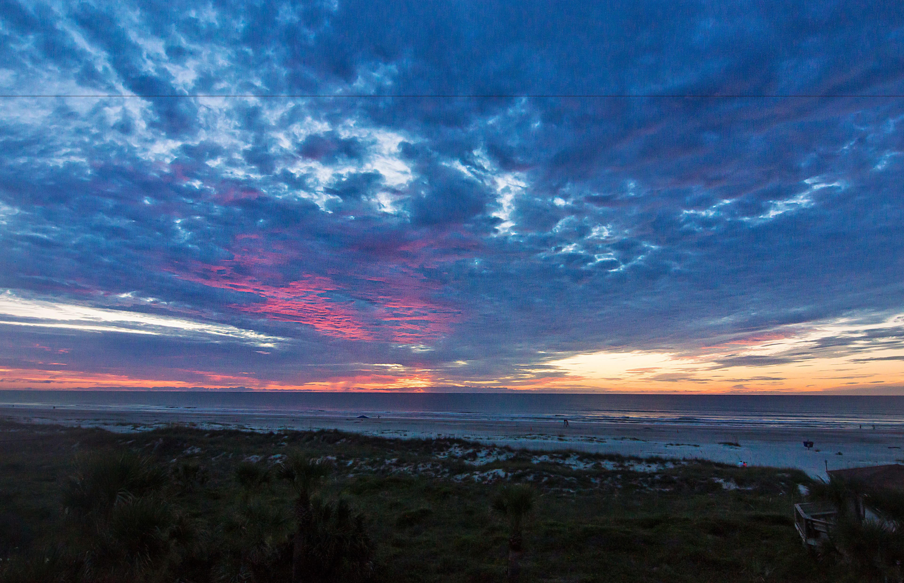 A beach with a sunset and clouds.